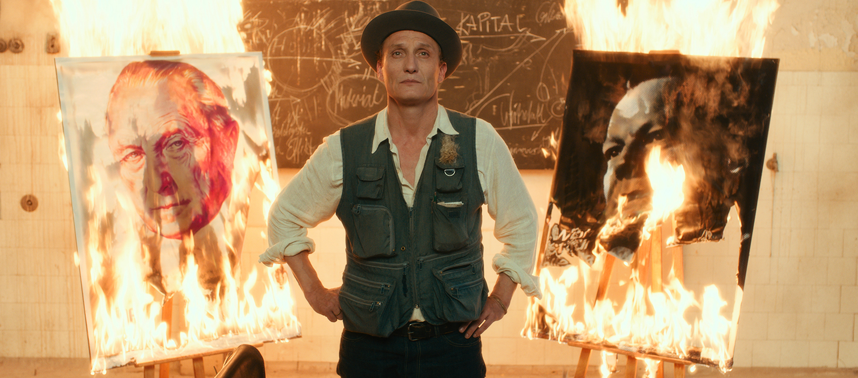 Man stands infront of two paintings on fire in Never Look Away