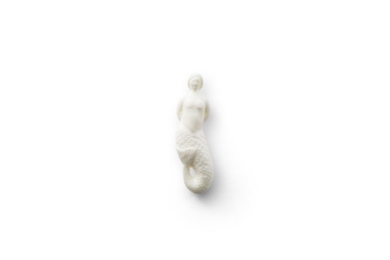 A white bar of soap shaped like the mermaid from The Lighthouse movie, sitting on a white background